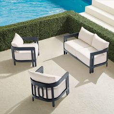 four pieces of furniture sitting on the ground next to a swimming pool with water in the background