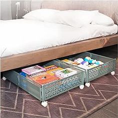 a bed sitting on top of a wooden floor next to two trays filled with magazines