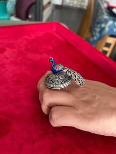 Elevate your style with our exquisite 925 silver peacock ring, handcrafted by skilled Indian artisans. This one-of-a-kind piece features a captivating rotating peacock design adorned with intricate stone and enamel work. Designed to stand out, this ring brings the beauty of the peacock to life, with every detail reflecting the artistry of India's heritage. Wear a symbol of grace and elegance while celebrating the essence of motion and creativity. Embrace the craftsmanship that makes this ring tr Peacock Design Jewelry For Party, Peacock Design Jewelry Gift, Peacock Design Jewelry As Gift, Peacock Design Jewelry For Gifts, Silver Peacock Design Jewelry For Party, Silver Fusion Jewelry With Peacock Design, Bohemian Jewelry With Peacock Design, Handmade Peacock Colored Jewelry For Weddings, Sterling Silver Peacock Design Jewelry