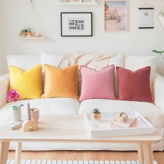 a living room with white couches and colorful pillows on the coffee table in front of it