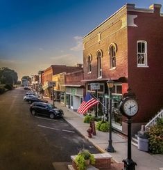 a street with cars parked on both sides and an american flag hanging from the building