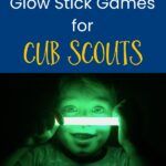 the cover of glow stick games for cub scouts, showing a young boy holding a flashlight in his hand