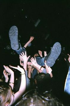 a group of people standing around each other with their feet in the air at a concert