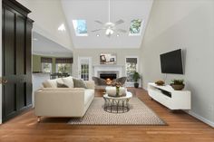 a living room with two couches and a television mounted on the wall in front of a fireplace