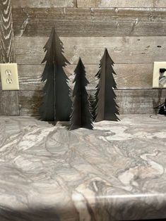 three metal trees are sitting on top of a marble countertop in front of wood planks