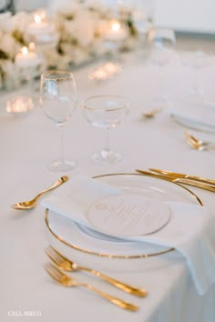 the table is set with white and gold place settings