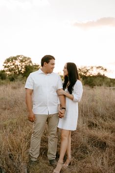 a man and woman standing in tall grass