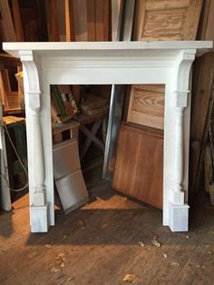 a white fireplace surround in a room with wood flooring