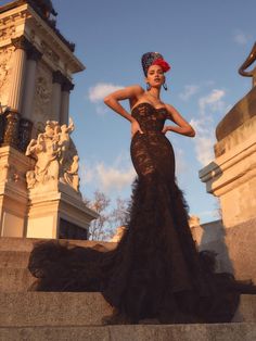 a woman in a black dress standing on some steps