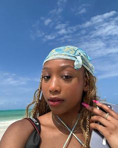 a woman with braids on her head is holding a cell phone and looking at the camera