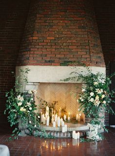 an image of a fireplace with candles and flowers on it