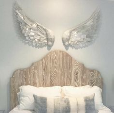 a bed with two angel wings on the headboard and pillows in front of it