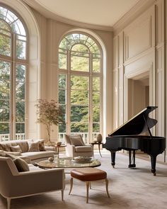 a grand piano in the middle of a living room with large windows and couches