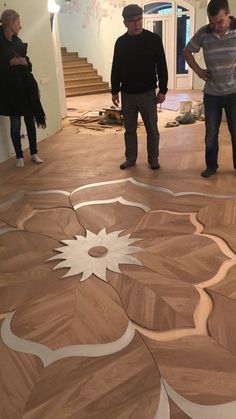 three people standing in an unfinished room with wood flooring on the ground and walls