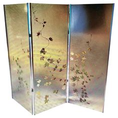 three - paneled screen with flowers and leaves painted on the glass, set against a white background