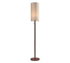 a floor lamp with a white shade on the top and a brown base, in front of a white background