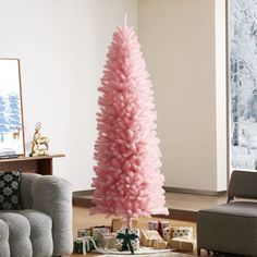 a pink christmas tree sitting in the middle of a living room with presents on the floor