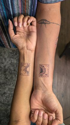 two people holding hands with tattoos on their arms