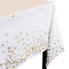 a white tablecloth with gold stars on it and a black metal stand underneath the table