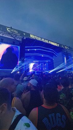 a large group of people standing in front of a stage with blue lights on it