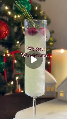 a glass filled with liquid sitting on top of a table next to a christmas tree