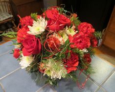 a bouquet of red and white flowers sitting on top of a blue tile countertop