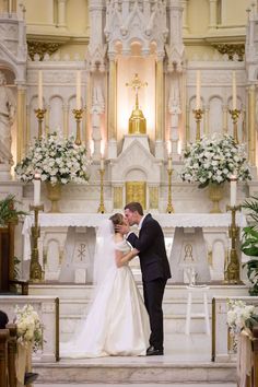 a bride and groom kissing in front of the alter