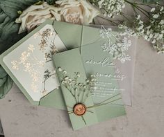 wedding stationery with flowers and greenery laid out on a table next to each other