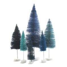 five different colored trees in white vases on a white surface with one blue and the other green