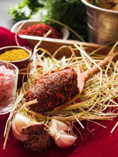 an assortment of spices and condiments on a red table cloth next to food