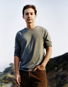 a man standing in front of a mountain with his hands on his hips and looking at the camera