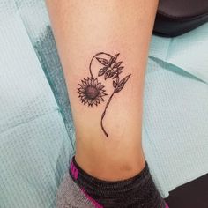 a woman's foot with a tattoo on it and a sunflower in the middle