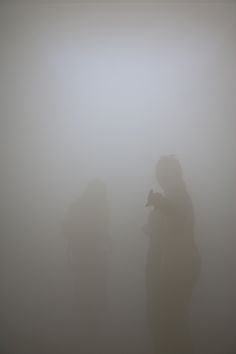 two people standing in the fog with their cell phones