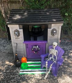 a toy house with a skeleton sitting on a purple lawn chair in front of it