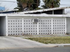 a white house with an open garage door on the side and palm trees in the background