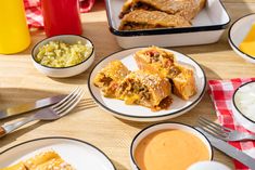 a table topped with plates of food and bowls of sauces on top of it