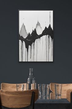 a black and white painting hanging on the wall above a dining room table with chairs