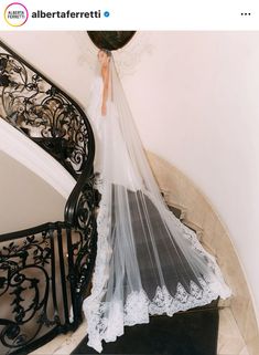 a bride is walking down the stairs in her wedding dress with a veil over her head