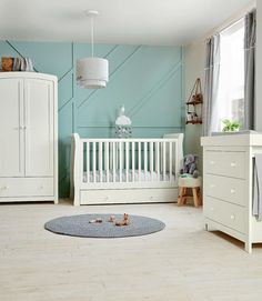 a baby's room with blue walls and white furniture