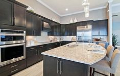 a large kitchen with granite counter tops and stainless steel appliances, along with dark wood cabinets