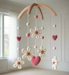 a crocheted mobile with flowers and hearts hanging from it's sides in front of a window