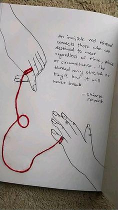 an open book with two hands holding a red string