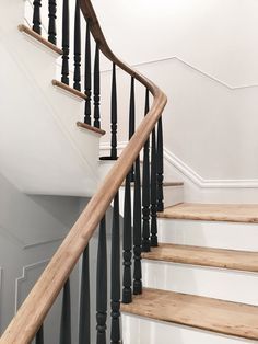 a staircase with black railing and wood handrails