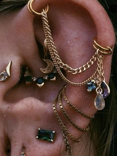 the ear is adorned with different types of jewels and gold chain bracelets that are attached to each ear