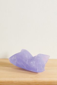 a purple plastic object sitting on top of a wooden table next to a white wall