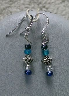 These earrings are made with silver flower spacer beads, blue seed beads, and black metallic seed beads. Silver-plated earring hooks and wire were used. Blue Beaded Metal Earrings, Blue Metal Beaded Earrings, Blue Dangle Earrings With Black Beads, Adjustable Blue Earrings With Black Beads, Blue Silver Beads Drop Earrings, Blue Silver Beaded Drop Earrings, Adjustable Silver Beaded Earrings With Black Beads, Adjustable Blue Beaded Earrings With Silver Beads, Blue Metal Beaded Earrings For Pierced Ears