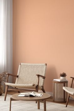 a living room with two chairs and a coffee table in front of a pink wall