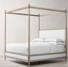 an iron bed frame with white sheets and pillows on the bottom, in a room