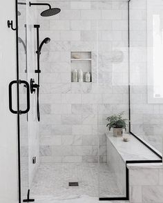 a white bathroom with black accents and marble tiles on the walls, along with a bathtub