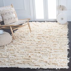 a white rug with fringes on the floor in front of a chair and window